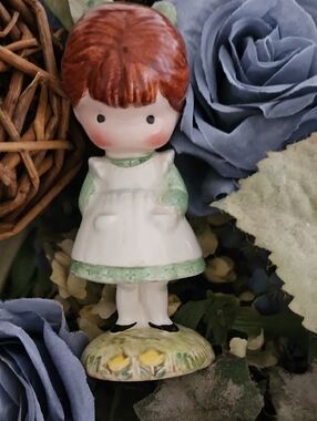 Porcelain Girl Figurine in White and Green Dress Holding A Doll Behond Her Back